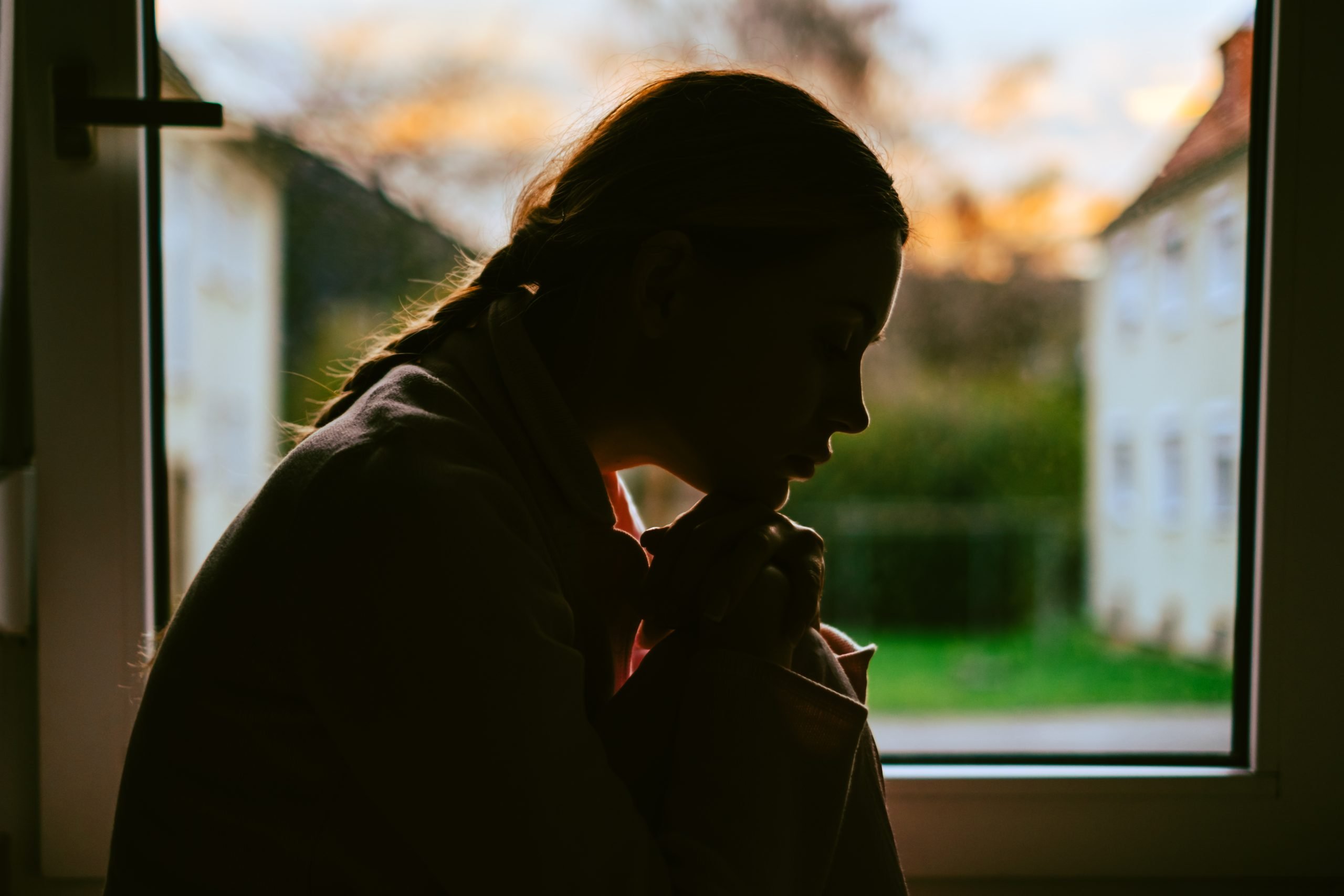 Young bored millennial woman looking at window alone at home. Fatigue or emotionally exhausted concept
